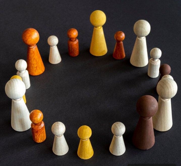 Bunte Holzspielfiguren in einem Kreis angeordnet, verschiedene Größen und Farben.